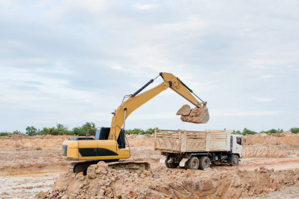istock Yellow excavator machine loading soil into a dump truck at construction site 961529378