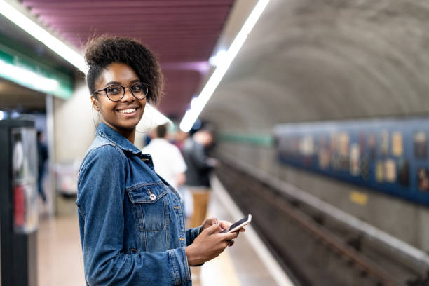 Young black woman with afro hairstyle using mobile in the subway Always Connected girl power photos stock pictures, royalty-free photos & images