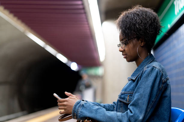 istock Young black woman with afro hairstyle using mobile in the subway 961531462