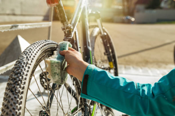 donna donna pulizia ruota bicicletta con spugna. - bike wash foto e immagini stock