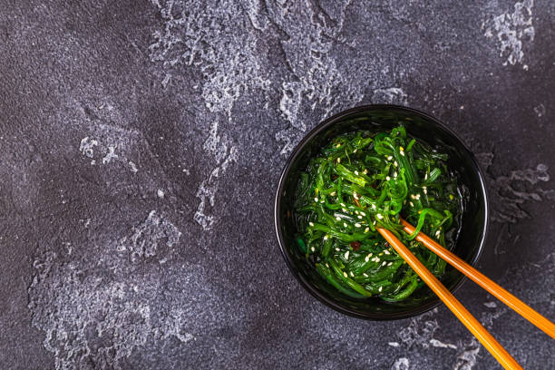 ensalada de algas chuka sobre fondo negro - wakame salad fotografías e imágenes de stock