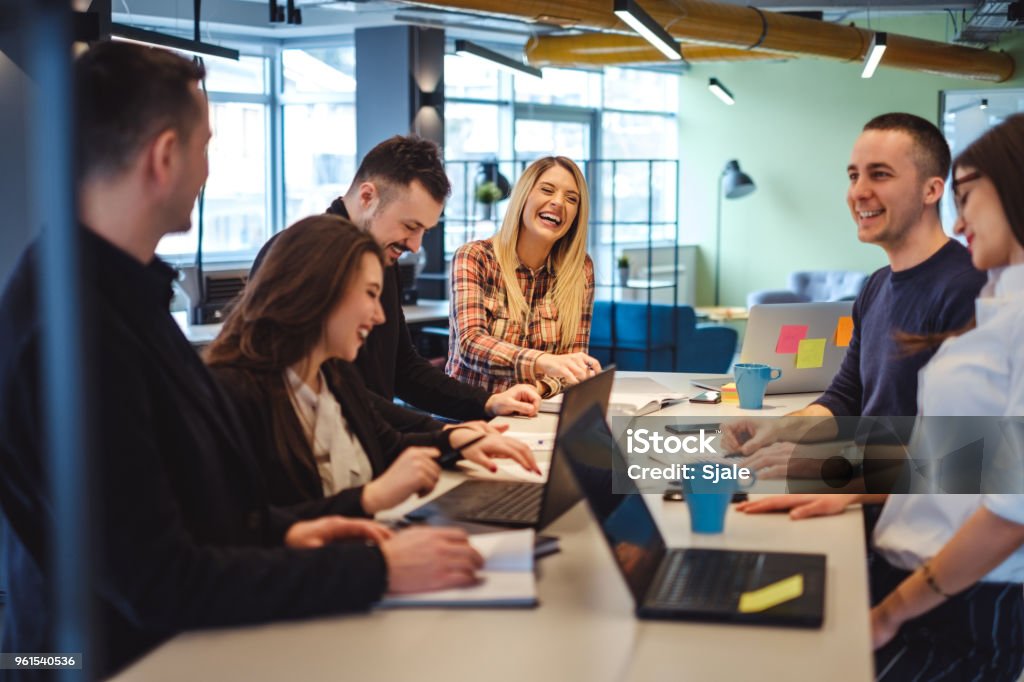 Happy colleagues laughing in the office meeting Happy colleagues laughing in the office at the meeting table Teamwork Stock Photo