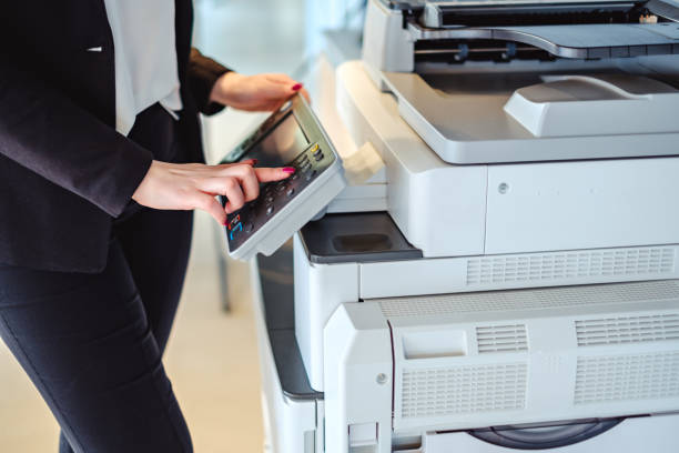 woman pressing button on a copy machine in the office - printout imagens e fotografias de stock