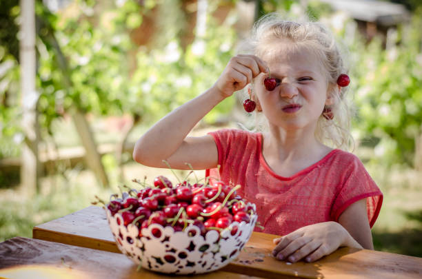 dziecko jedzące owoce wiśni - juicy childhood colors red zdjęcia i obrazy z banku zdjęć