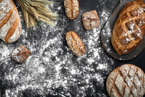 istock Different bread with flour and spikelets of wheaton black background 961552324