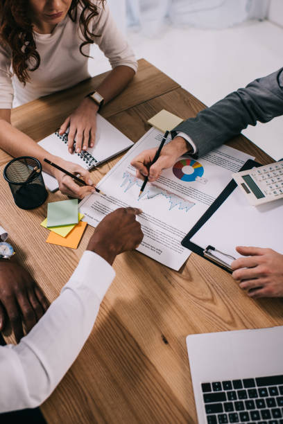 team of business partners doing paperwork while sitting at table - planning manager paperwork business imagens e fotografias de stock