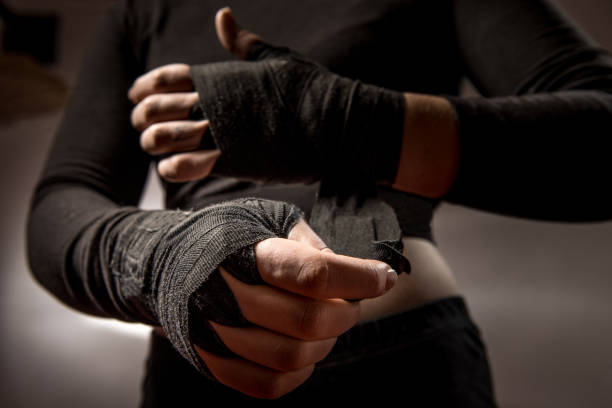 joven boxeador atar vendaje protector alrededor de sus muñecas - ready to fight fotografías e imágenes de stock