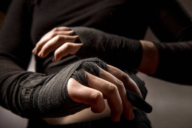 istock Young Woman Boxer Tying Protective Bandage Around Her Wrists 961553190