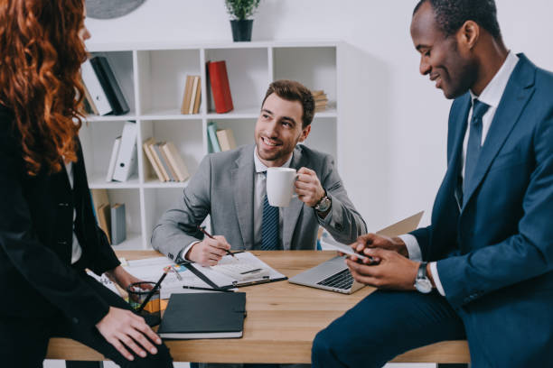 istock Smiling estate agent with cup of coffee talking to clients 961553552