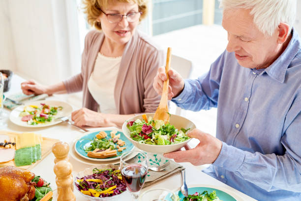 dziadkowie korzystających z jedzenia na rodzinnej kolacji - couple dinner summer sunlight zdjęcia i obrazy z banku zdjęć