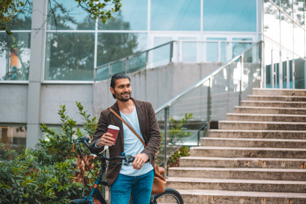 istock Photo of a handsome man having coffee while leading bike 961561184