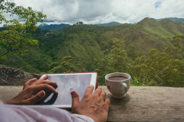 istock Woman using digital tablet PC sitting outdoor and drinking tea. 961562422