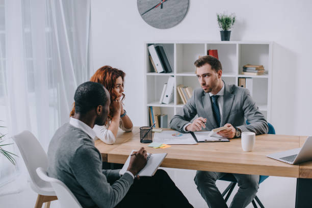 istock Estate agent with interracial couple sitting at table in office 961565310