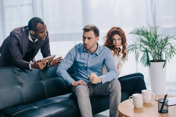 istock Counselor with clipboard talking to young couple sitting on sofa 961566688