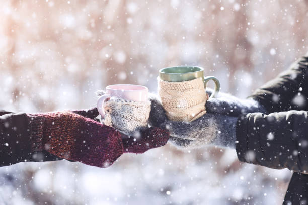 istock Couple hands in mittens take a mugs with hot tea in winter park 961571412