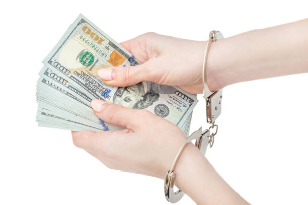 istock Woman's hands in handcuffs holding money. Isolated on white. 961575932