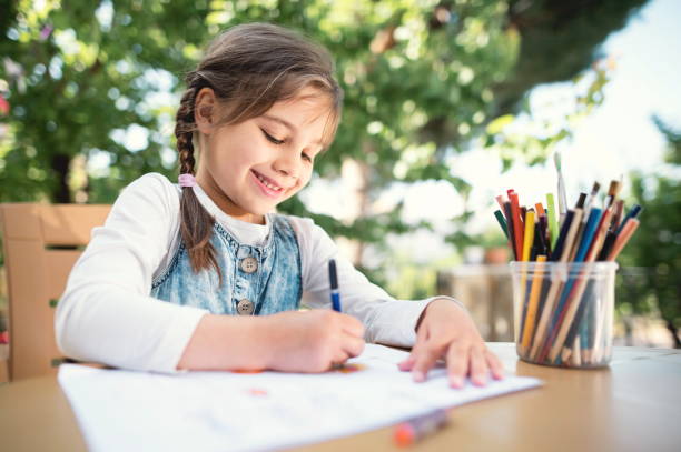 Child Girl Drawing Picture Outdoors in Summer stock photo