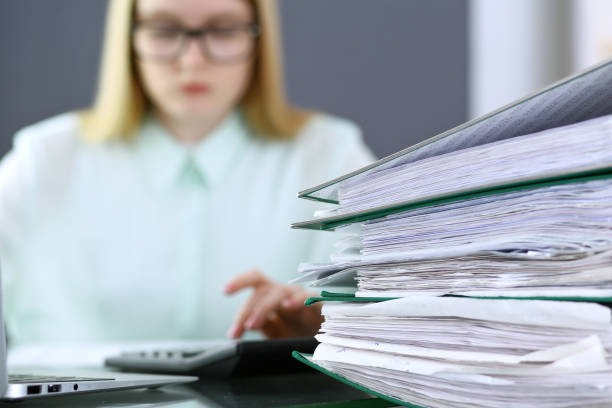 istock Bookkeeper or financial inspector  making report, calculating or checking balance. Binders with papers closeup. Audit and tax service concept. Green colored image backgroun 961580890
