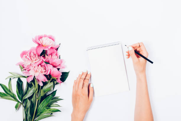 scrivania femminile stilizzata con bouquet di peonie fresche rosa chiaro - diary writing women human hand foto e immagini stock