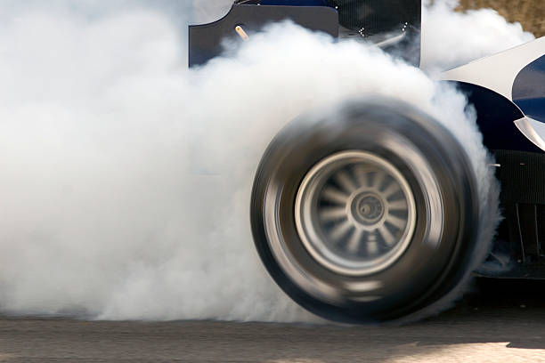 Formula One Car Wheelspin 2006 Formula One Grand Prix car smoking its super slick tires.  The Formula One Grand Prix car is engulfed in white smoke. throttle photos stock pictures, royalty-free photos & images