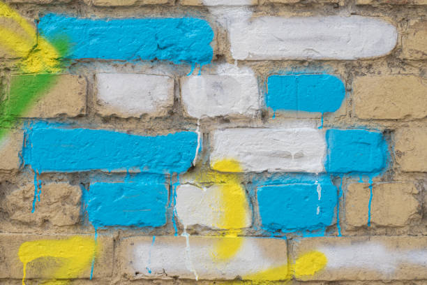 istock Several painted bricks in blue, yellow and white on an old dirty wall, as graffiti. Colorful grunge texture of wall. Abstract modern background 961603084