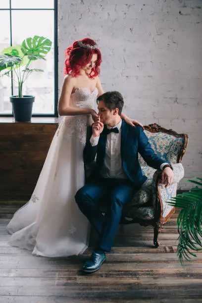 Photo of newlyweds are sitting in a vintage chair in the loft