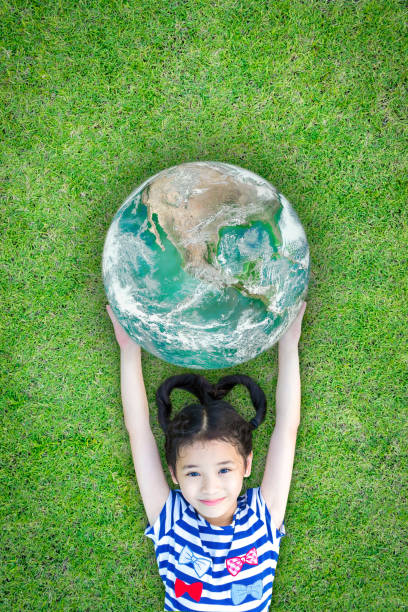 istock Ecology concept with happy kid raising green globe on eco friendly green grass lawn. Element of image furnished by NASA 961633984