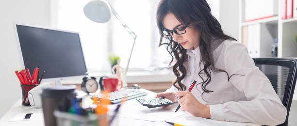 istock A young girl is sitting at the office desk, working with a calculator and documents. 961634042