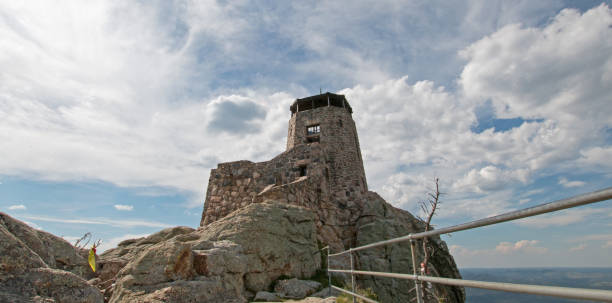 Black Elk Peak [formerly known as Harney Peak] Fire Lookout Tower under cumulus cloudscape in Custer State Park in the Black Hills of South Dakota United States