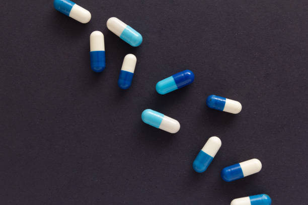 istock Heap of pills spreaded over color table. Group of assorted white and blue tablets. 961645092