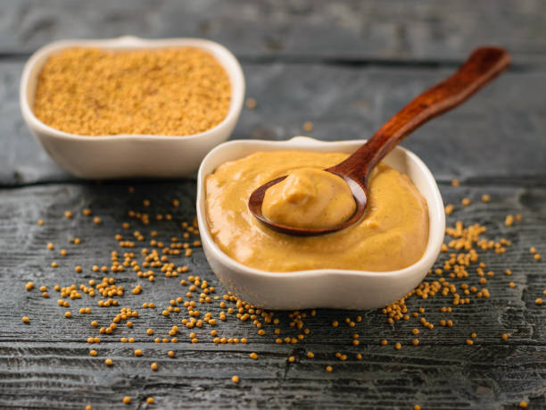 deux bols et verser la sauce de graines et la moutarde sur une table rustique foncée. - moutarde assaisonnements et vinaigrettes photos et images de collection