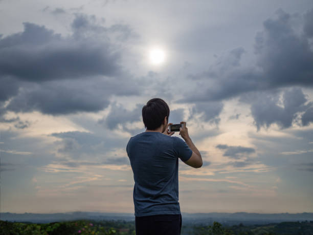 istock Man taking picture from phone with sunset and evening sky 961681974