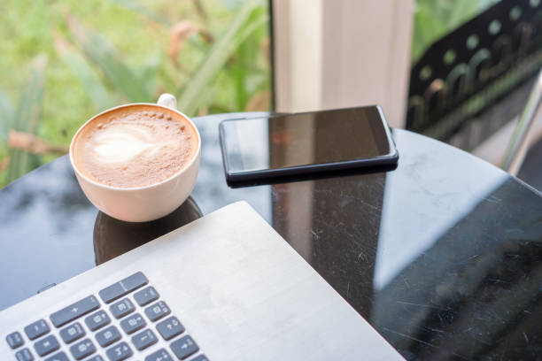 istock Hot Latte coffee with laptop and smartphone on glass table 961682052