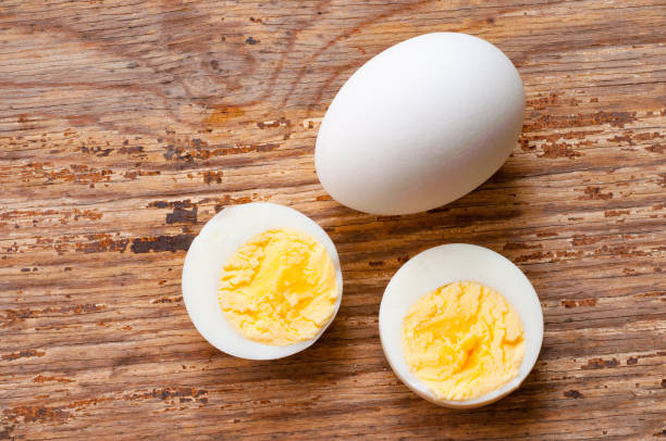 ritaglio di uova sode e uovo crudo con guscio su sfondo di legno - hard cooked egg foto e immagini stock
