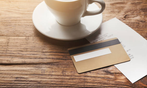 Restaurant bill and credit card on wooden table Restaurant bill for coffee and credit card on wooden table, paying for lunch at cafe, copy space restaurant table card stock pictures, royalty-free photos & images