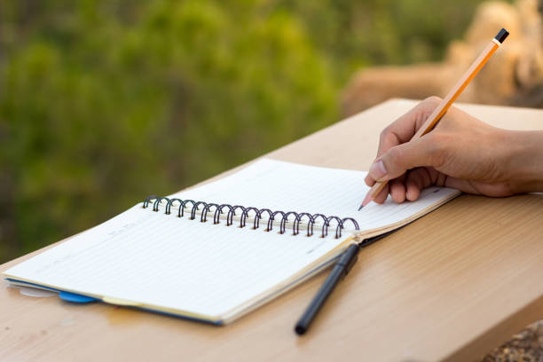 istock A young woman writing a notebook on a wooden table to plan an education. 961713198