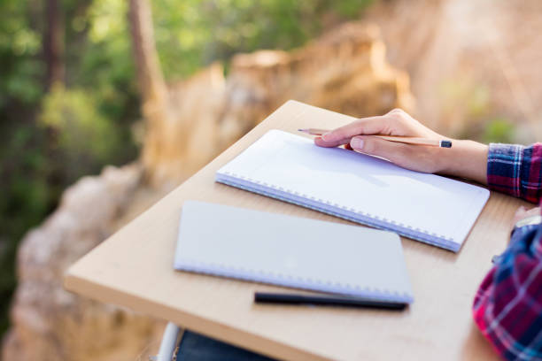 istock A young woman writing a notebook on a wooden table to plan an education. 961713246