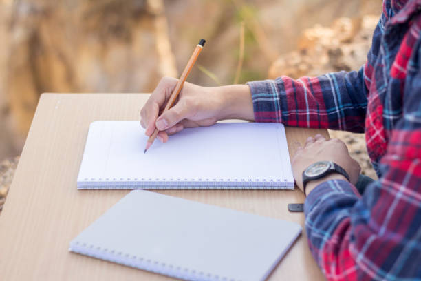 istock A young woman writing a notebook on a wooden table to plan an education. 961713252