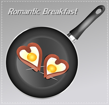 Scrambled eggs with sausage in a heart shape in the pan. Romantic breakfast.