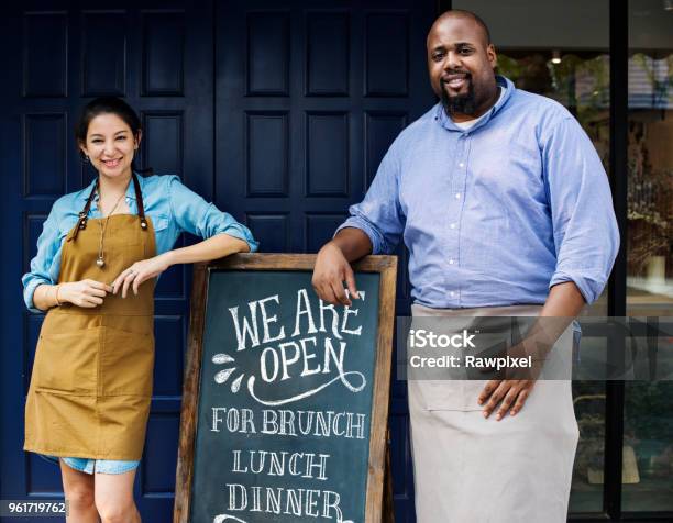 Cheerful Business Owners Standing With Open Blackboard Stock Photo - Download Image Now