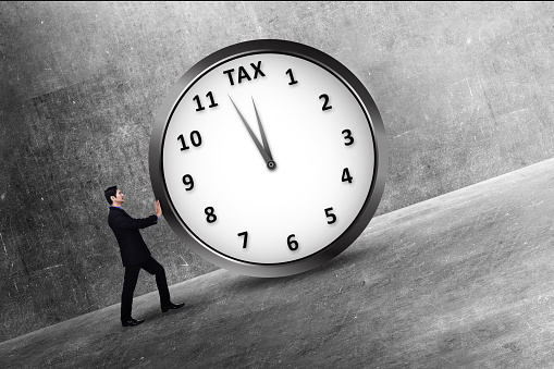Attractive asian businessman pushing a clock with Tax deadline. Taxation concept