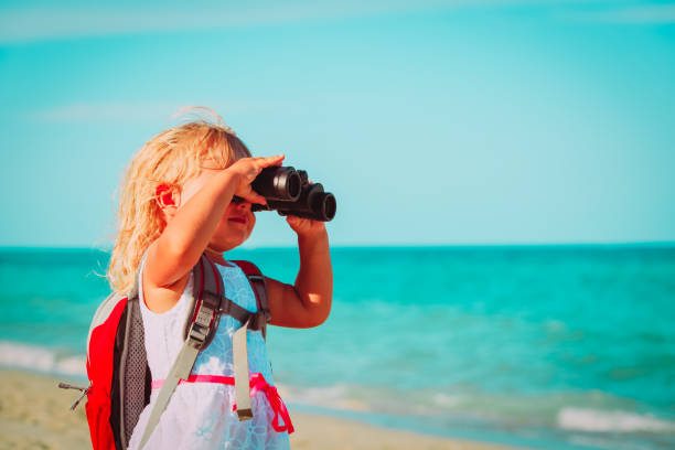 istock little girl travel on beach, looking through binocular 961721220