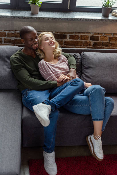 istock high angle view of happy african american man hugging girlfriend while resting on sofa together 961721366