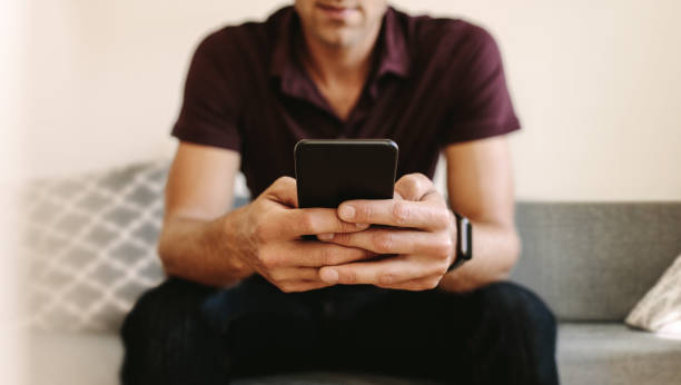 istock Man looking at mobile phone sitting at home 961721522
