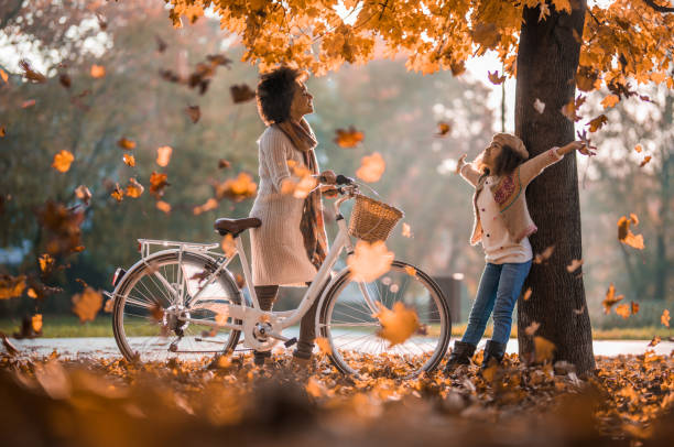 carefree african american mother and daughter enjoying among autumn leaves at the park. - family african ethnicity black african descent imagens e fotografias de stock