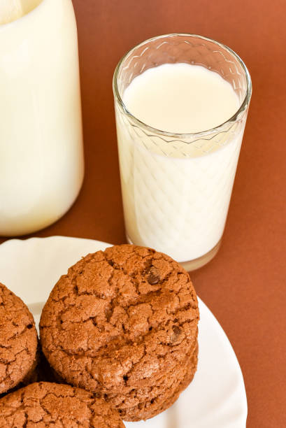 Milk in clear glass bottle and in glass glass Cup and cookies on  white plate