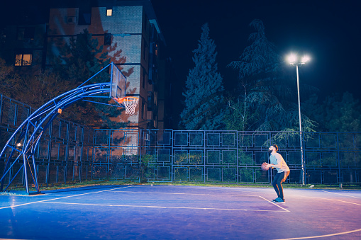 Young handsome bearded men playing basketball outdoors