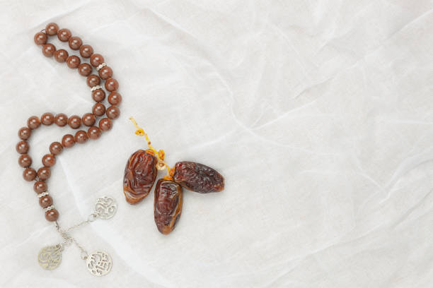 istock Table top view aerial image of decorations Ramadan Kareem holiday background.Flat lay objects dates with brown prayer beads on white cloth at office desk.free space for creative design text and content. 961741734