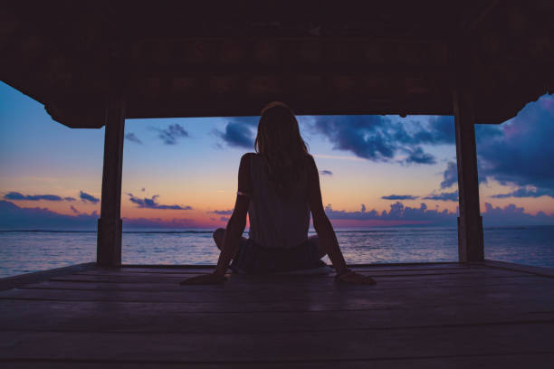 silhouette d’une jeune fille profitant de lever / coucher de soleil sur une pagode de l’océan. - zen like women temple meditating photos et images de collection