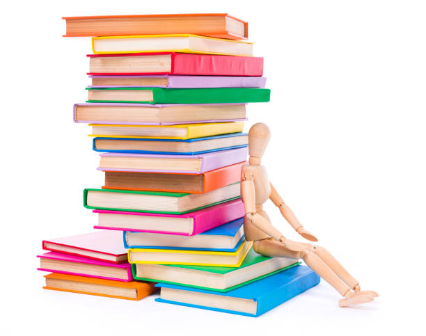 istock Wooden dummy puppet sitting on books 961757370